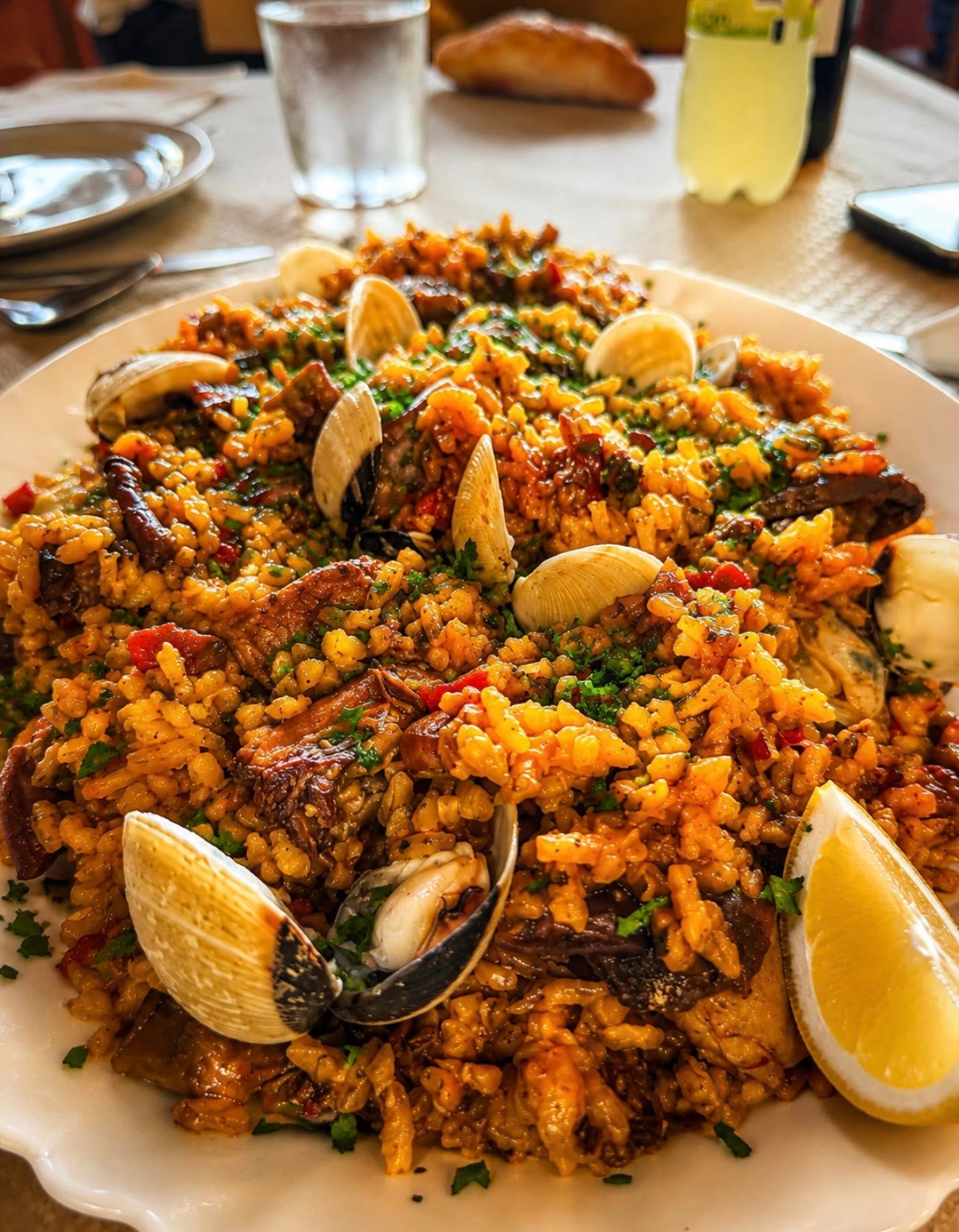 Arroz con almejas servido en mesa junto a pan y bebida